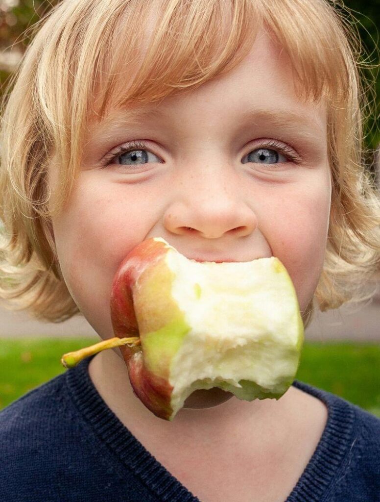 Young boy eating an apple.