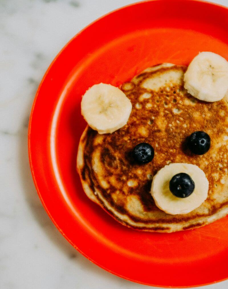 Pancake with bananas and blueberries. Looks like a cute animal face.